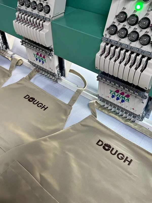 ตัวอย่างผ้ากันเปื้อนปักโลโก้ DOUGH ผลิตโดย POLOBB